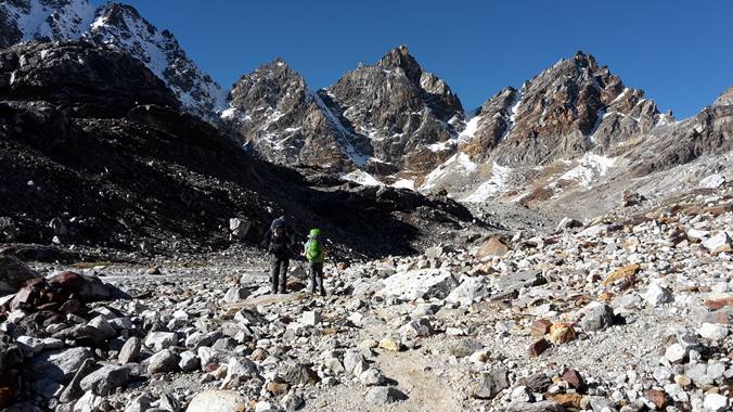 Zwei Wanderer in einer weiten felsigen Hochgebirgslandschaft